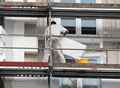 Bauarbeiter dämmt Haus mit Polystyrol