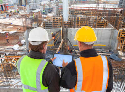 Zwei Bauingenieure mit Tablet an Baustelle